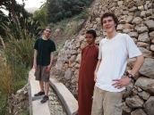 Alex, Ahmed and Adam stand on the falaj going down to Wadi Tiwi in Oman