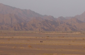 three Omani ladies in abayas walk across a wide expanse